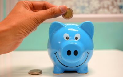 Hand inserting a coin into a blue piggy bank for savings and money management.